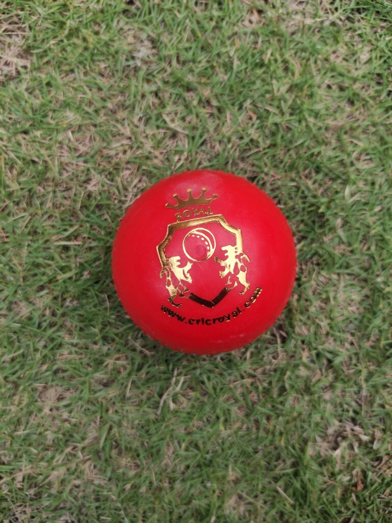 Red Molded Regular Synthetic Cricket Hard Ball, also known as Knocking Ball, shown from front view with Royal Cricket logo printed on top, ideal for knocking practice and bat conditioning