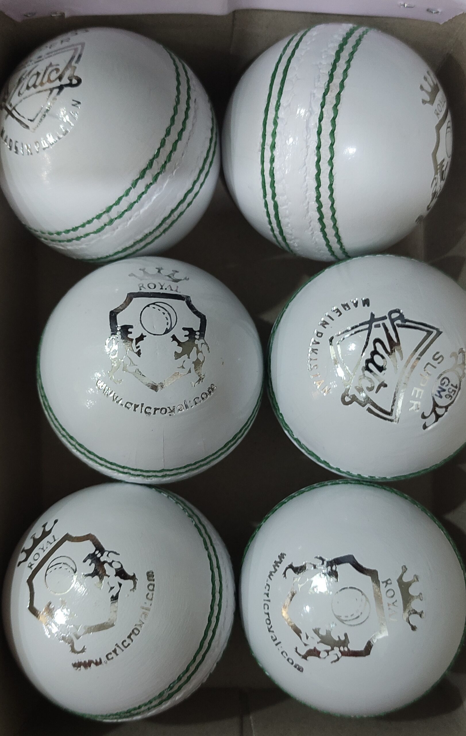 A set of 6 white genuine leather cricket balls with hand-sewn raised seams, placed in a box and displayed from multiple angles, ideal for club-level and professional use.