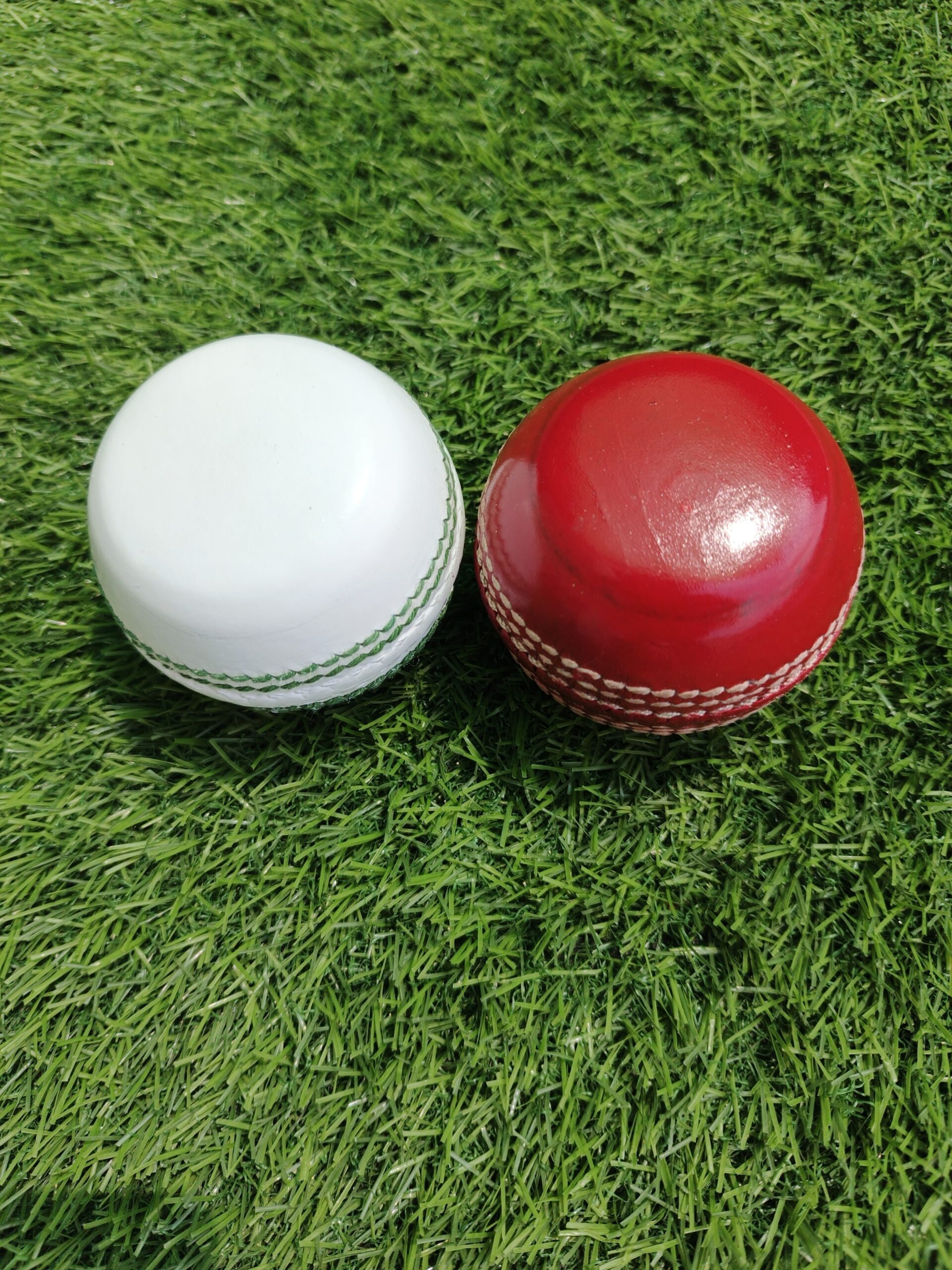 Front view of flat-style seam bowler coaching and training cricket balls in red and white colors, designed for accurate grip, spin, and seam practice; ideal for developing bowling technique