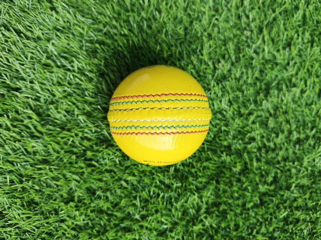 Yellow Indoor Premium Leather Cricket Ball shown from side view with full tight stitching visible across the seam, crafted for durable indoor use with premium quality finish