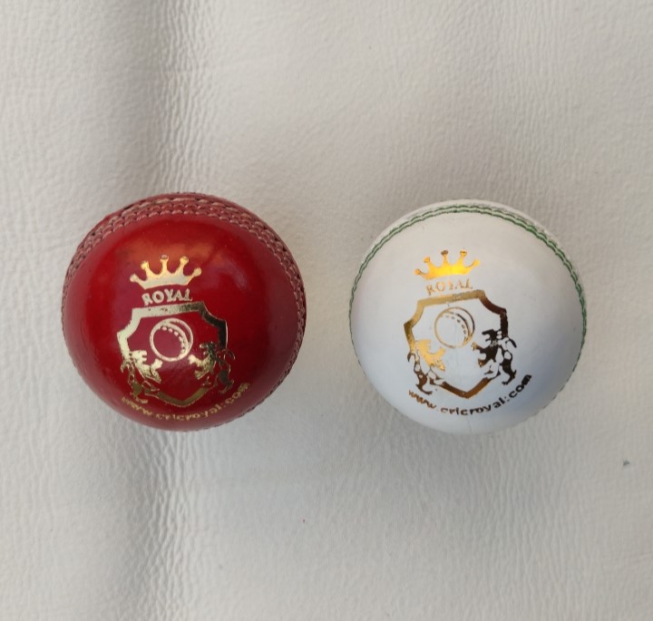 Two premium alum tanned leather cricket balls, one red and one white, placed side by side in front view — highlighting smooth finish and seam quality.