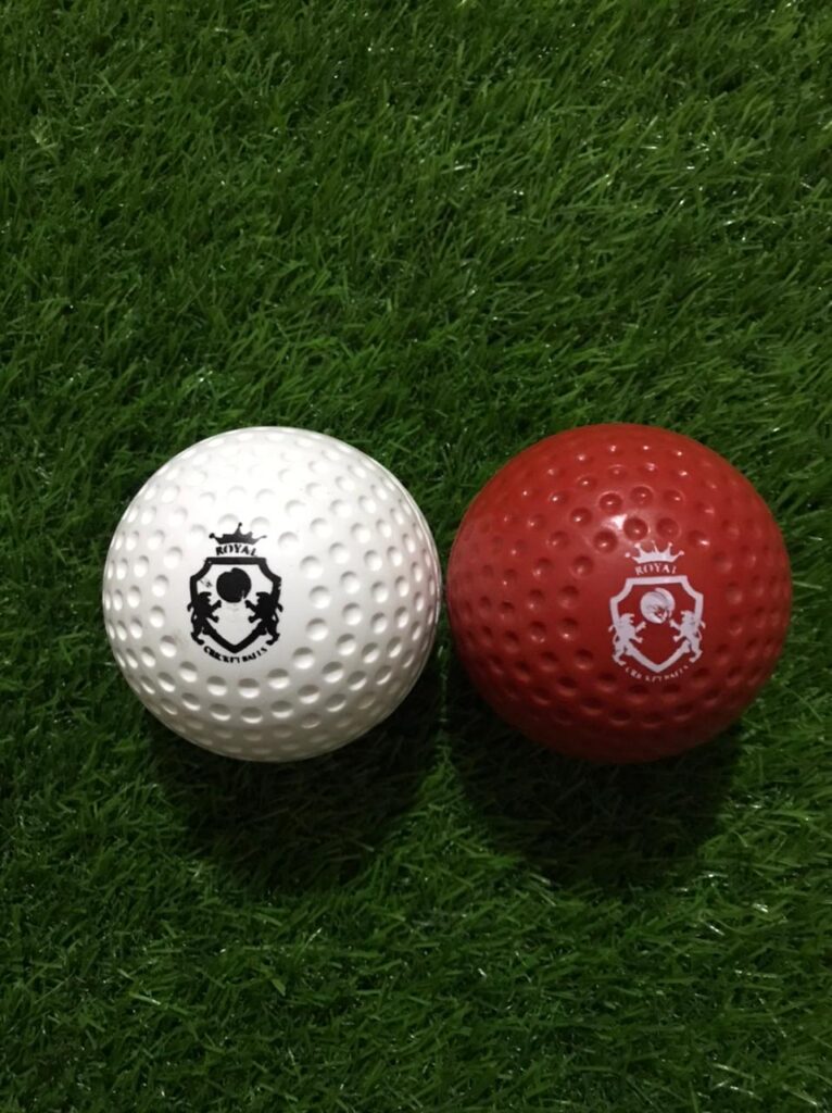 Pair of Dimple Molded Synthetic Cricket Hard Balls in red and white colors, both shown from front view with Royal Cricket logo printed clearly on the surface and dimple texture for enhanced swing control