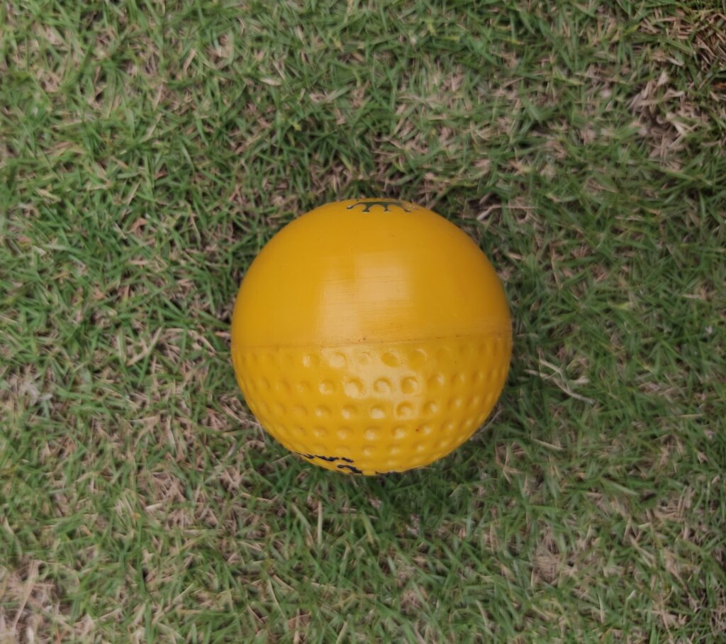 Yellow Swing Technique Molded Synthetic Cricket Hard Ball shown from side view, highlighting its aerodynamic shape and dual-surface design ideal for swing training and match-style practice