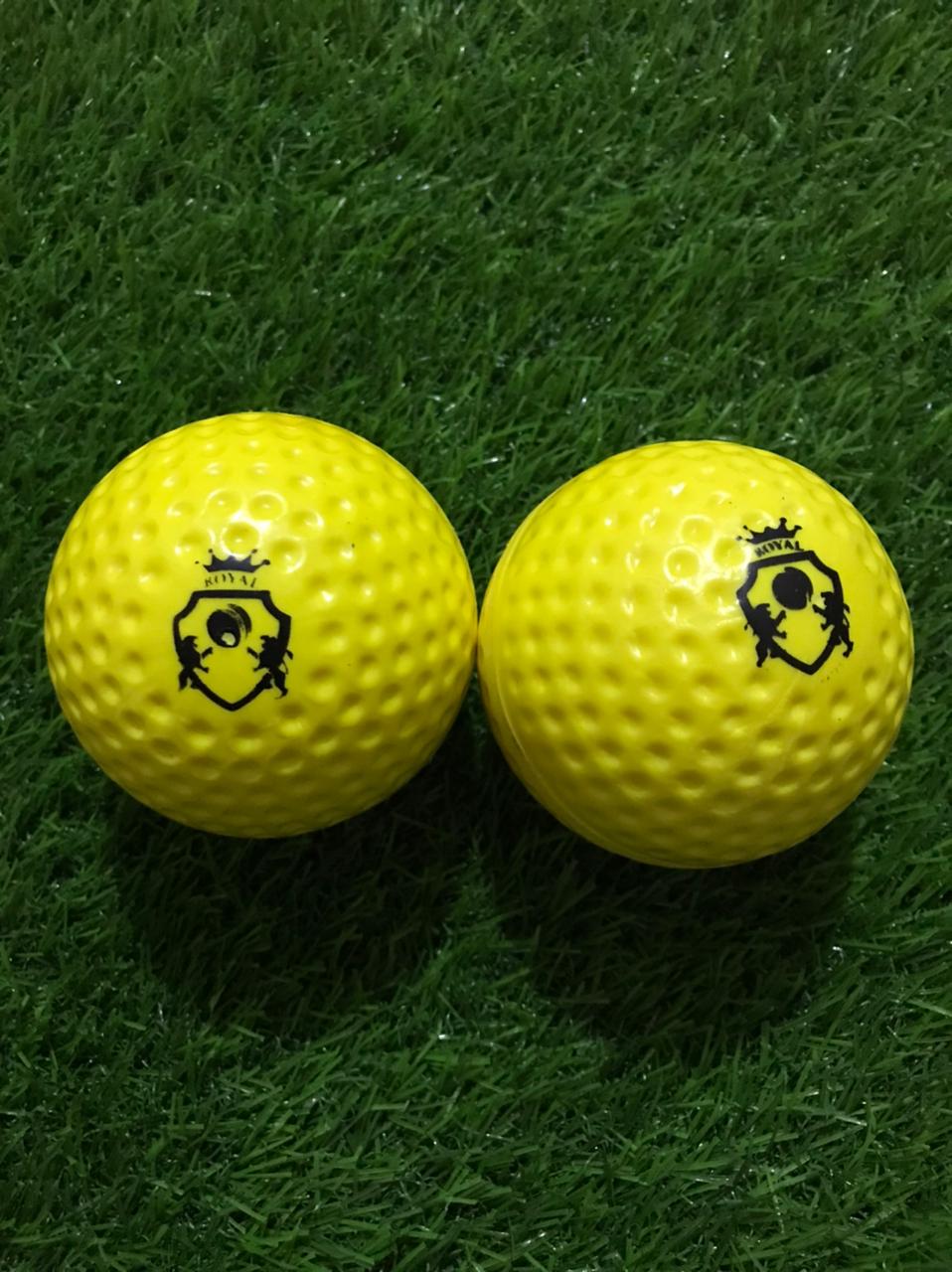 Two yellow Dimple Soft Molded Synthetic Cricket Balls placed on green grass, both showing their front side with clearly visible company logos, ideal for outdoor practice sessions.