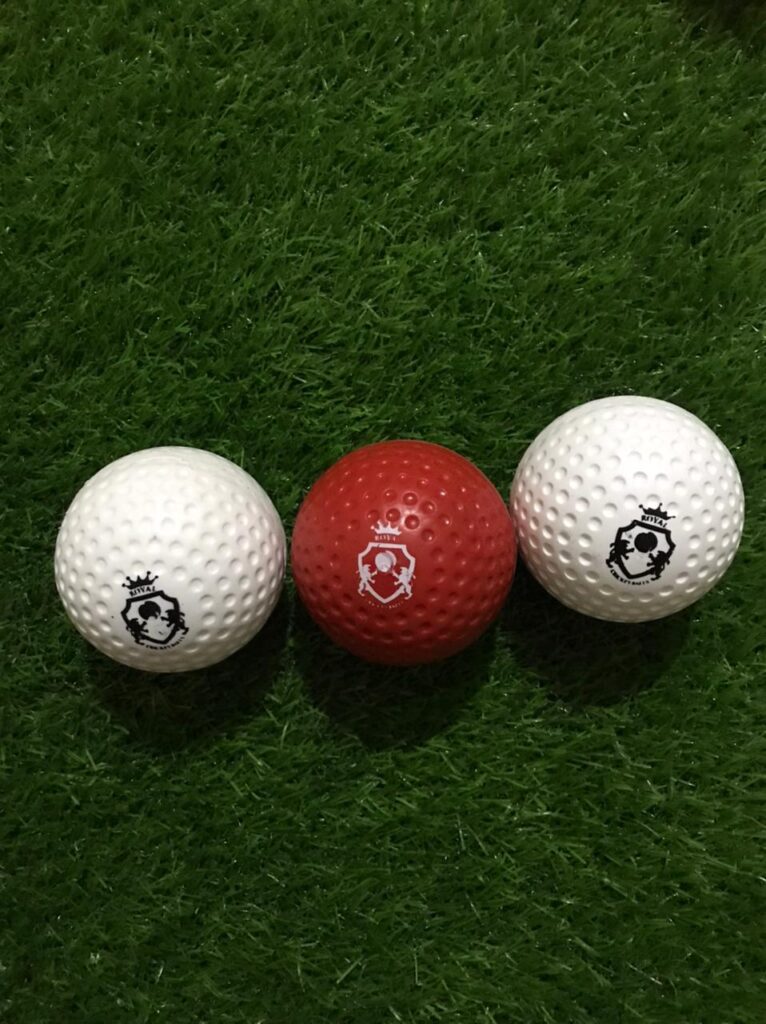Set of 3 dimple bowling machine balls in red and white colors, placed at varied angles to display surface holes and overall design suited for machine practice